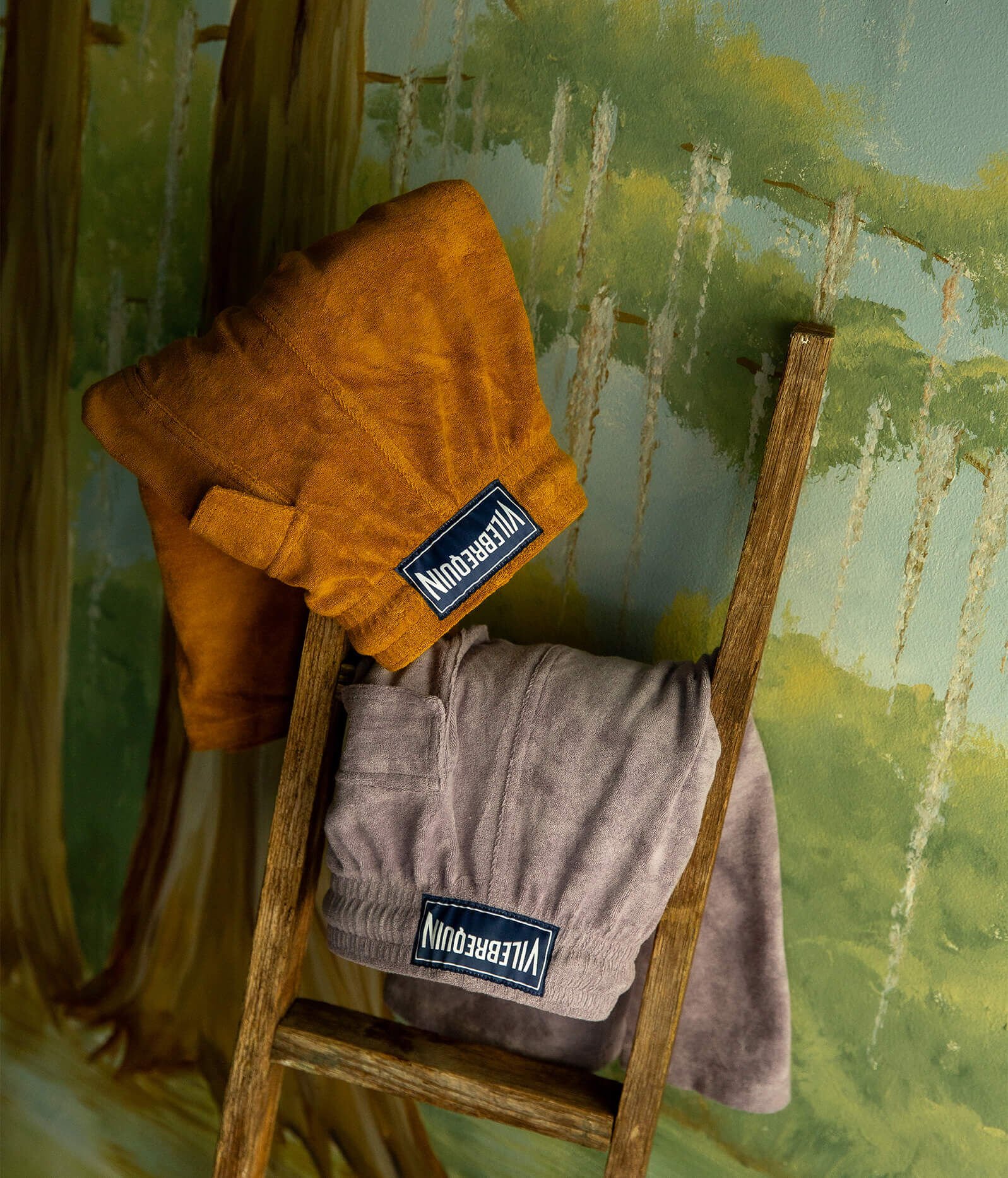 Two pairs of terrycloth shorts resting on a wooden ladder.